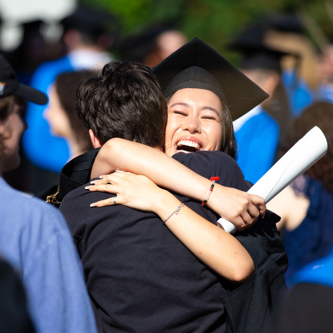 Two UCD alumni hugging and smiling at their graduation.